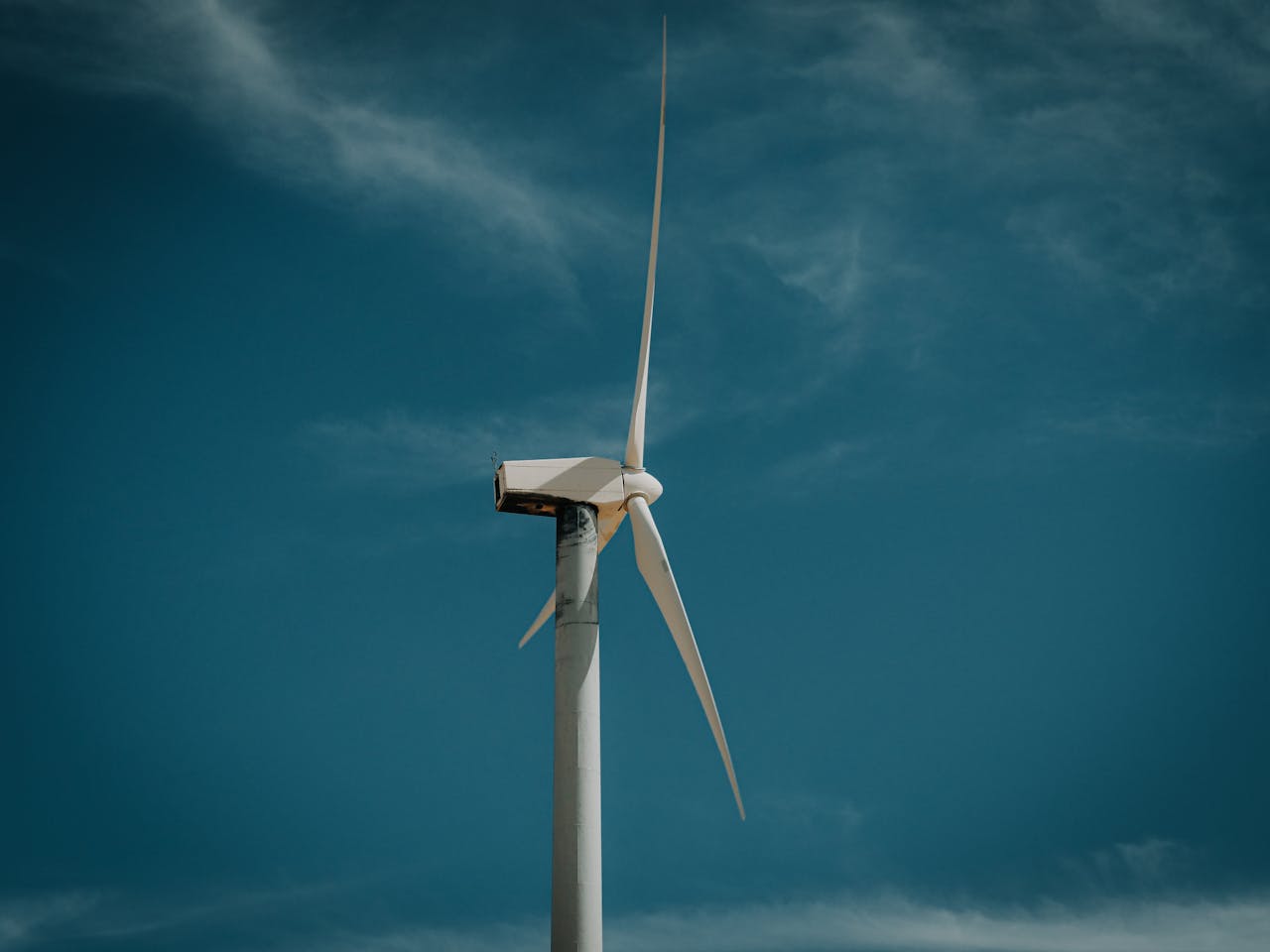 Wind turbine against a clear blue sky, symbolizing renewable energy.
